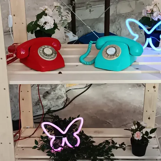 Un teléfono rojo y uno azul están sobre un estante de madera.