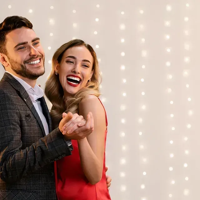 Un hombre con traje y corbata sostiene a una mujer con un vestido rojo.