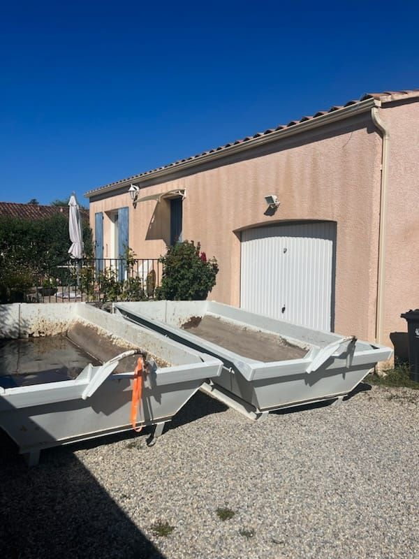 Deux bennes à ordures rectangulaires devant une maison
