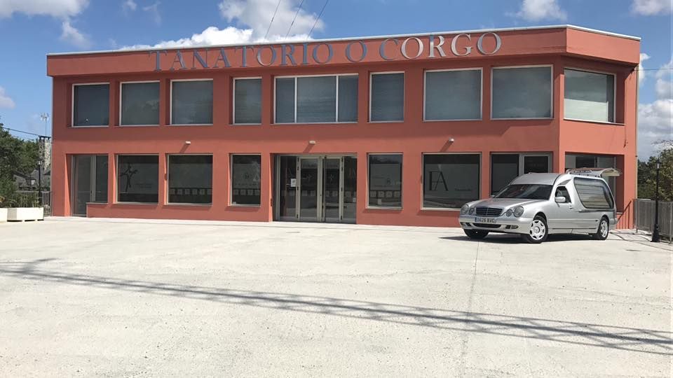 Un coche fúnebre está aparcado delante de un gran edificio.