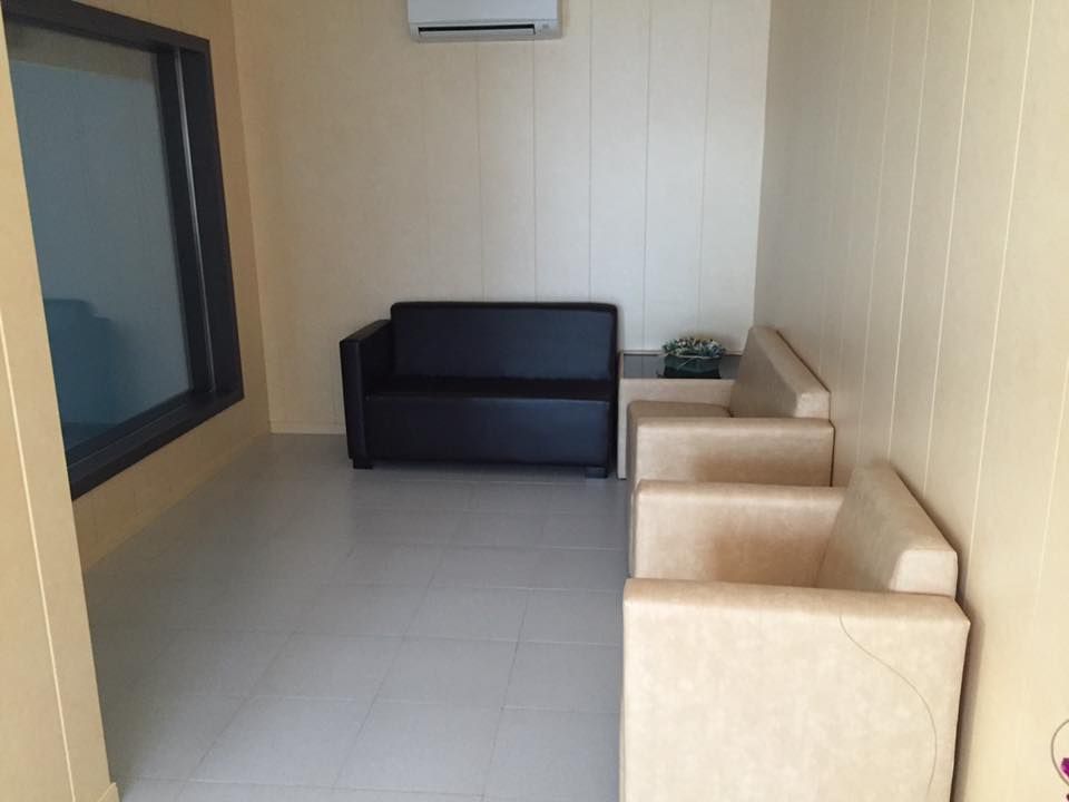 Una sala de espera con un sofá, sillas y una ventana.