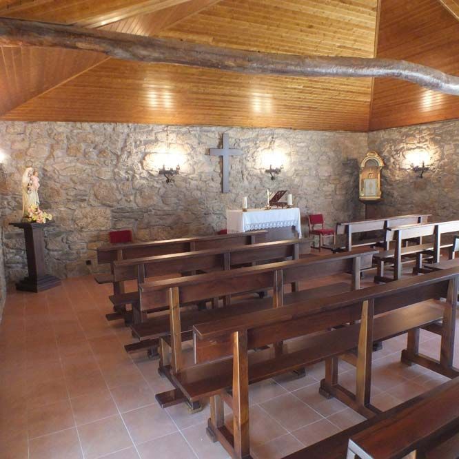 Una iglesia con bancos de madera y una cruz en la pared