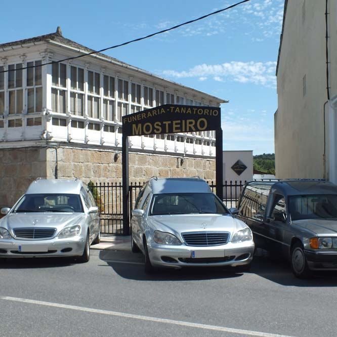 Tres coches están aparcados bajo un cartel que dice mosteiro
