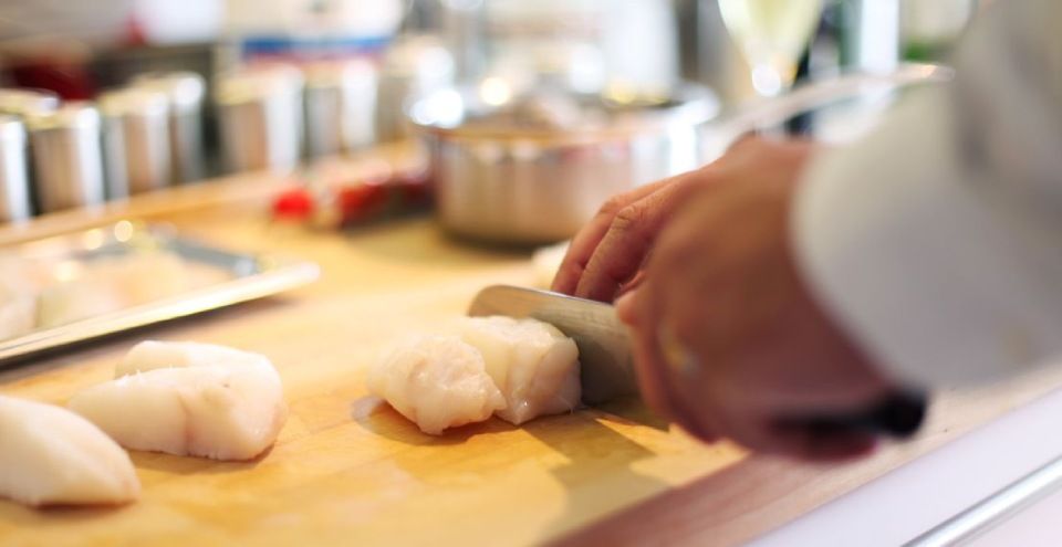 Une personne coupe un morceau de poisson sur une planche à découper.