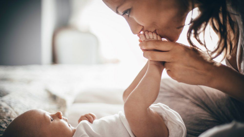 Femme en train d'embrasser les pieds d'un bébé