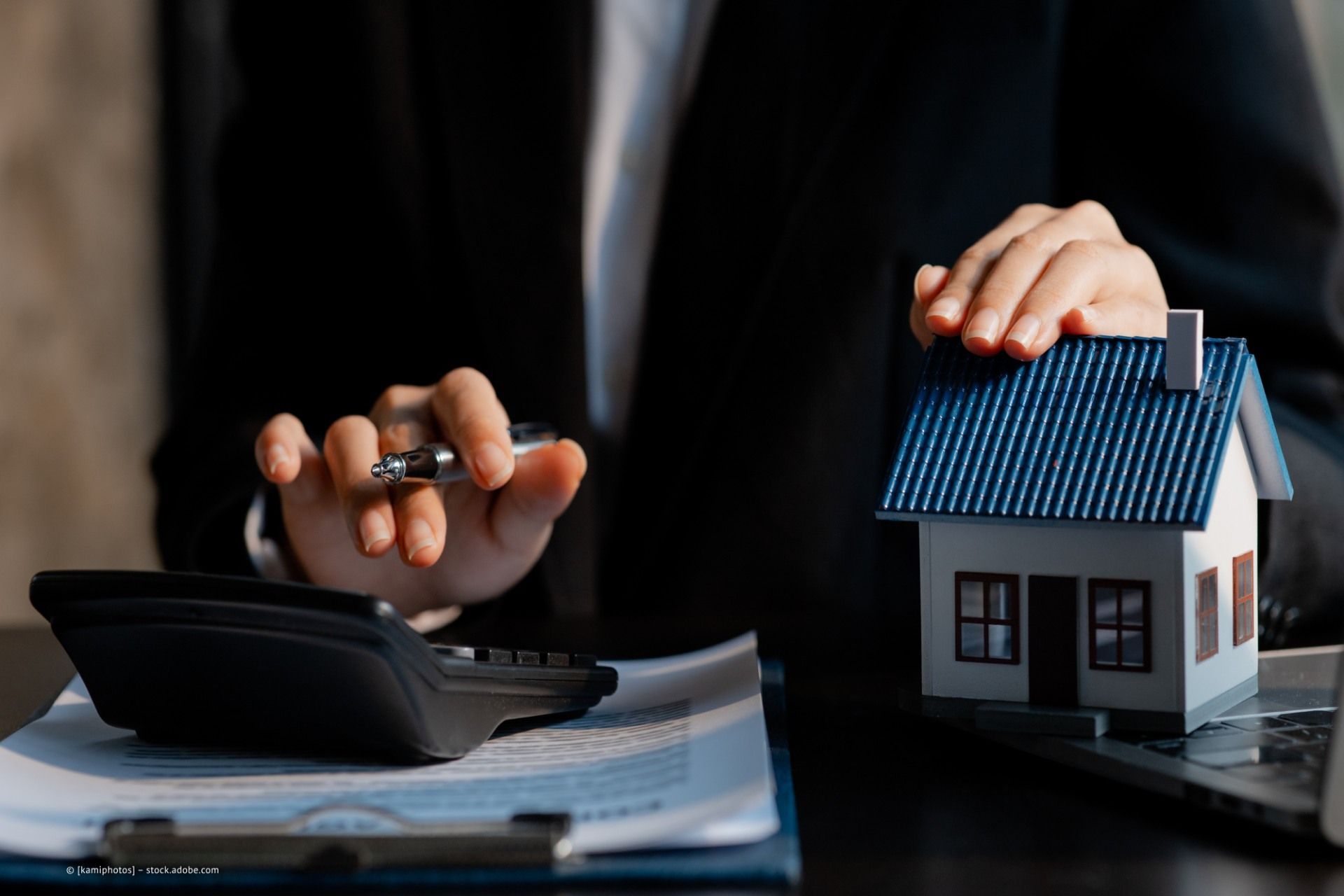 Person zeigt auf ein Modellhaus