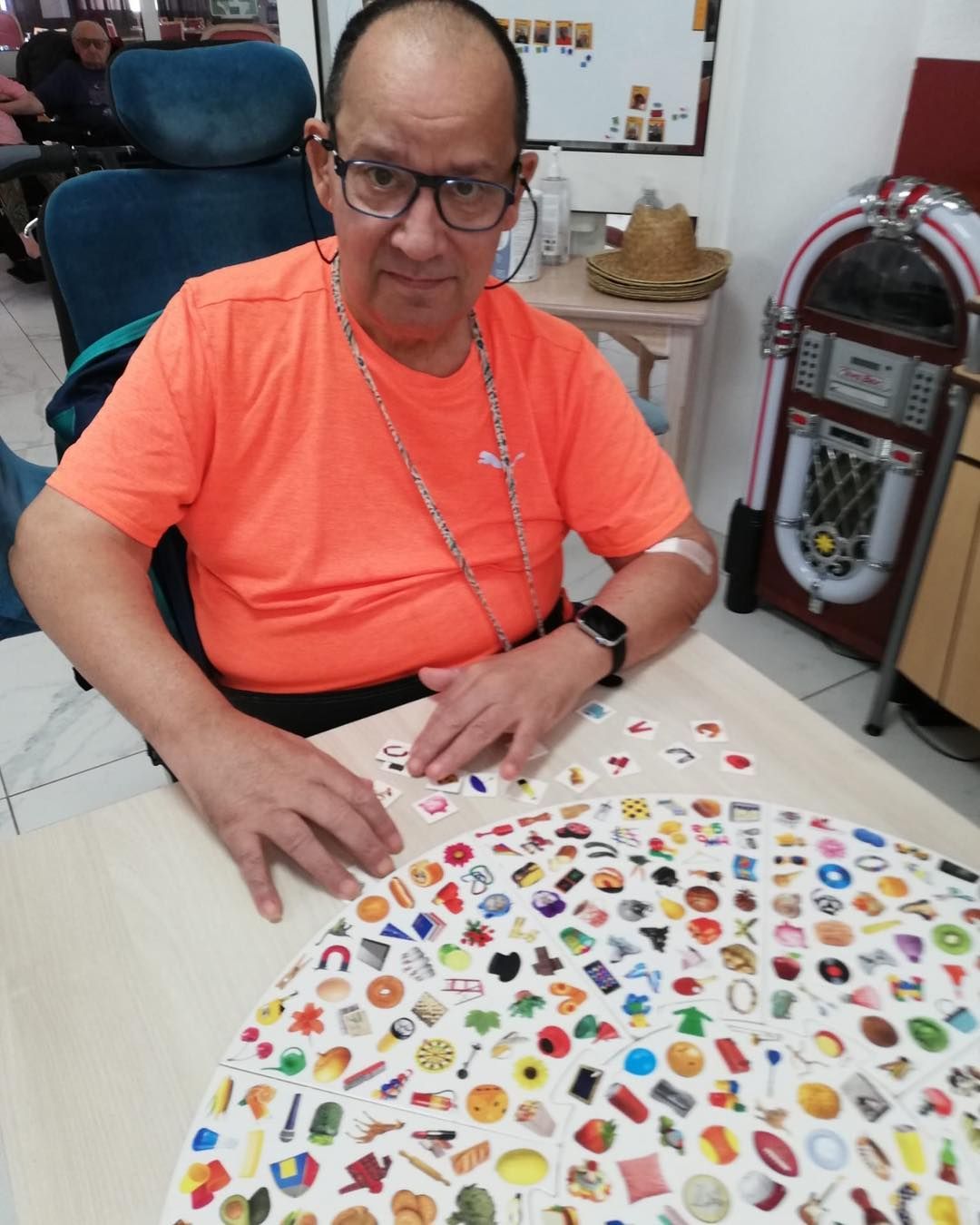 Une personne âgée est assise à une table, en train de trier de petites pièces de jeu circulaires.