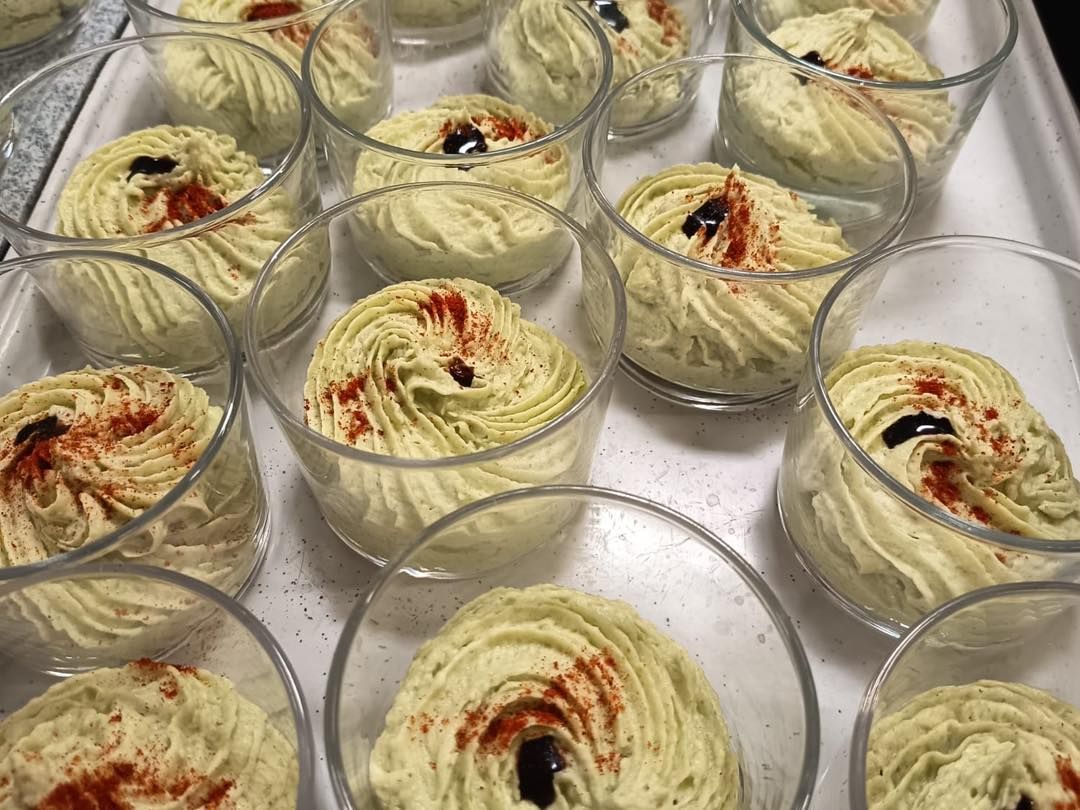 Petits bols en verre de dessert crémeux saupoudré de cannelle, disposés sur un plateau.