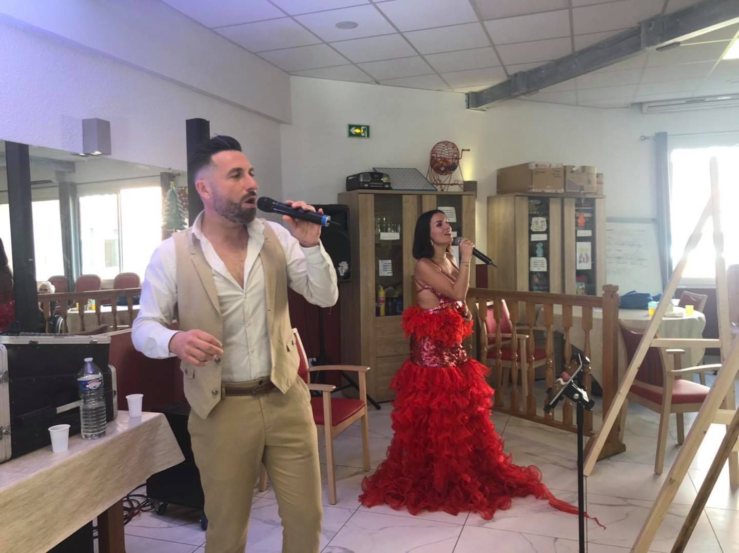 Un homme et une femme habillés en tenues de type flamenco chantent dans des microphones.