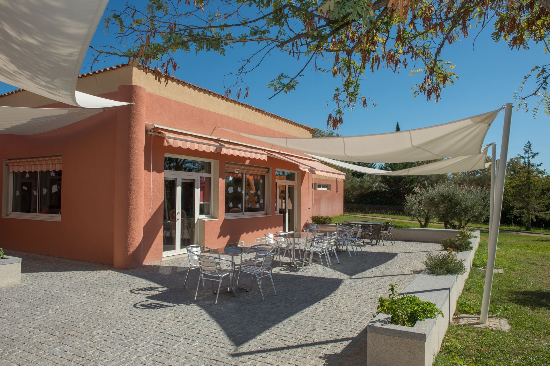 Un bâtiment orange clair avec une terrasse en gravier aménagée.