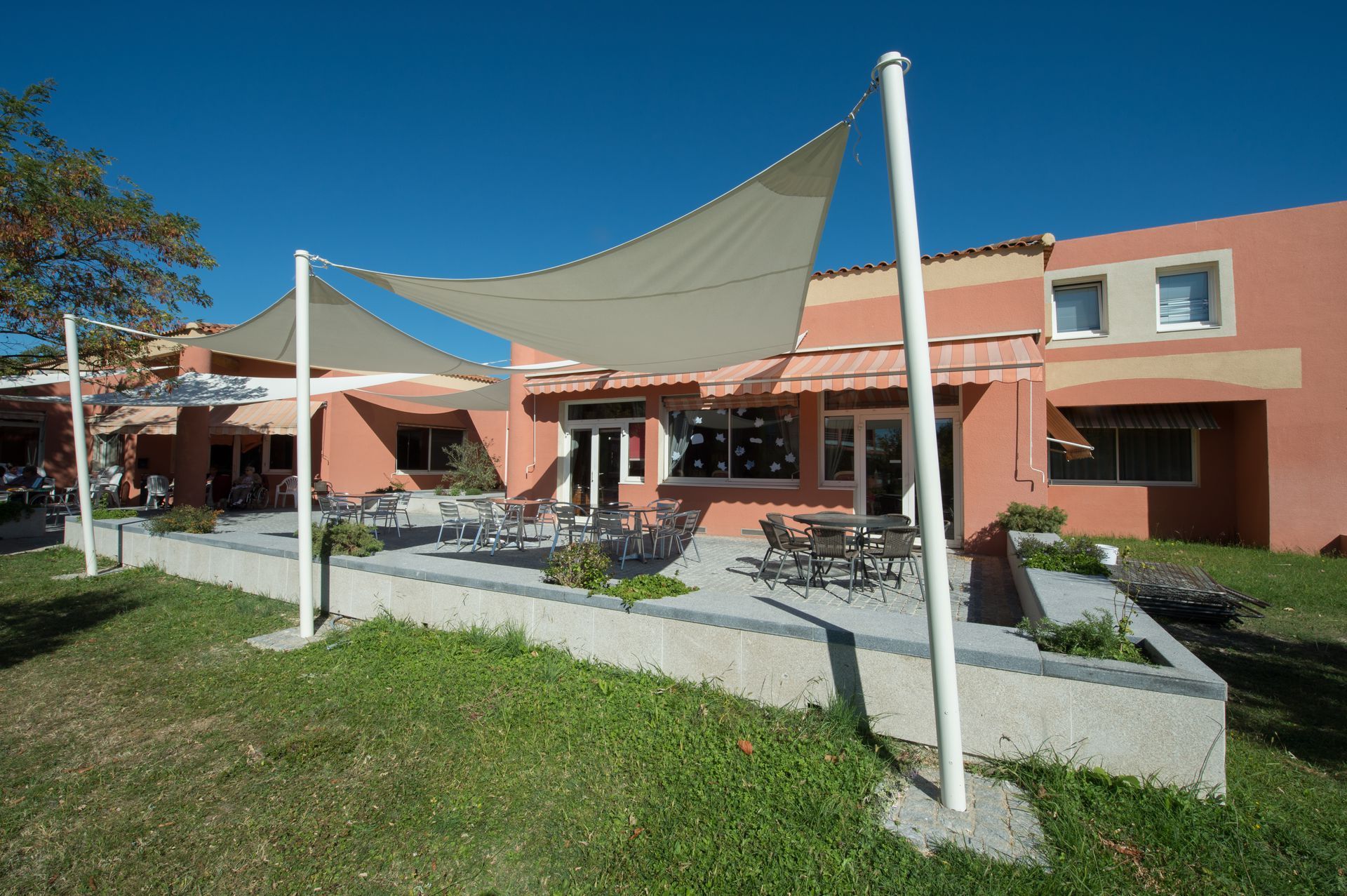 Une terrasse extérieure baignée de soleil avec des tables à manger.