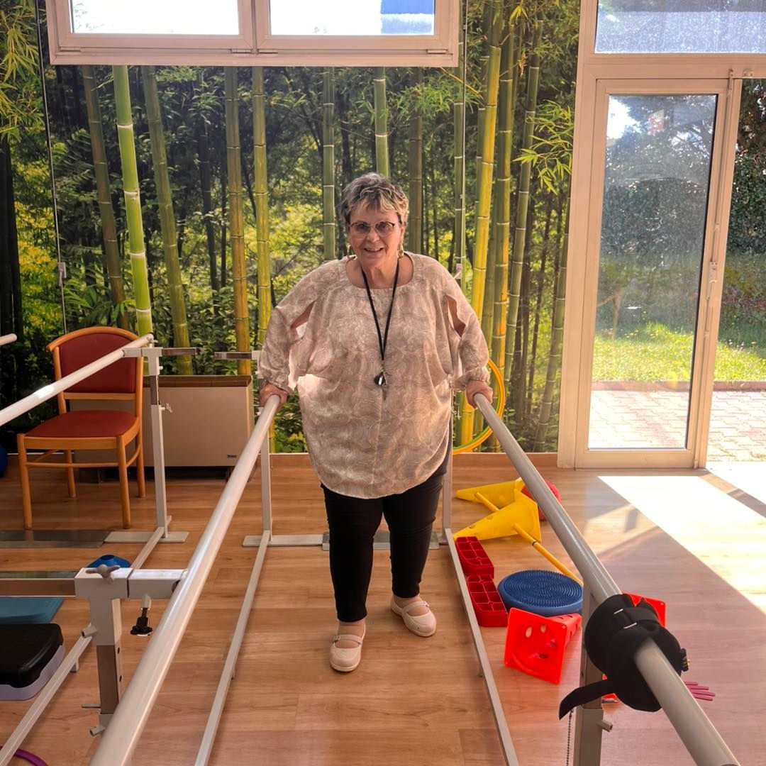Une personne utilise des barres parallèles dans une salle de thérapie lumineuse.
