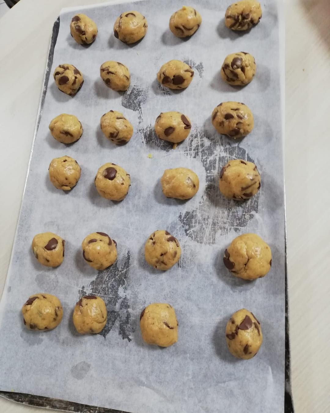 Plateau de boules de pâte à biscuits aux pépites de chocolat non cuites sur du papier sulfurisé