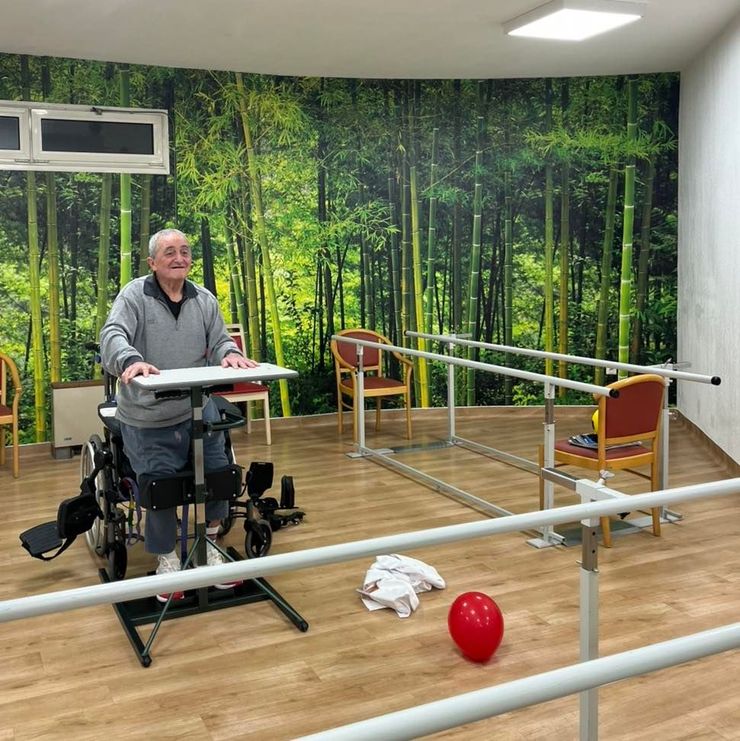 Une personne en fauteuil roulant se tient debout à une table de physiothérapie.