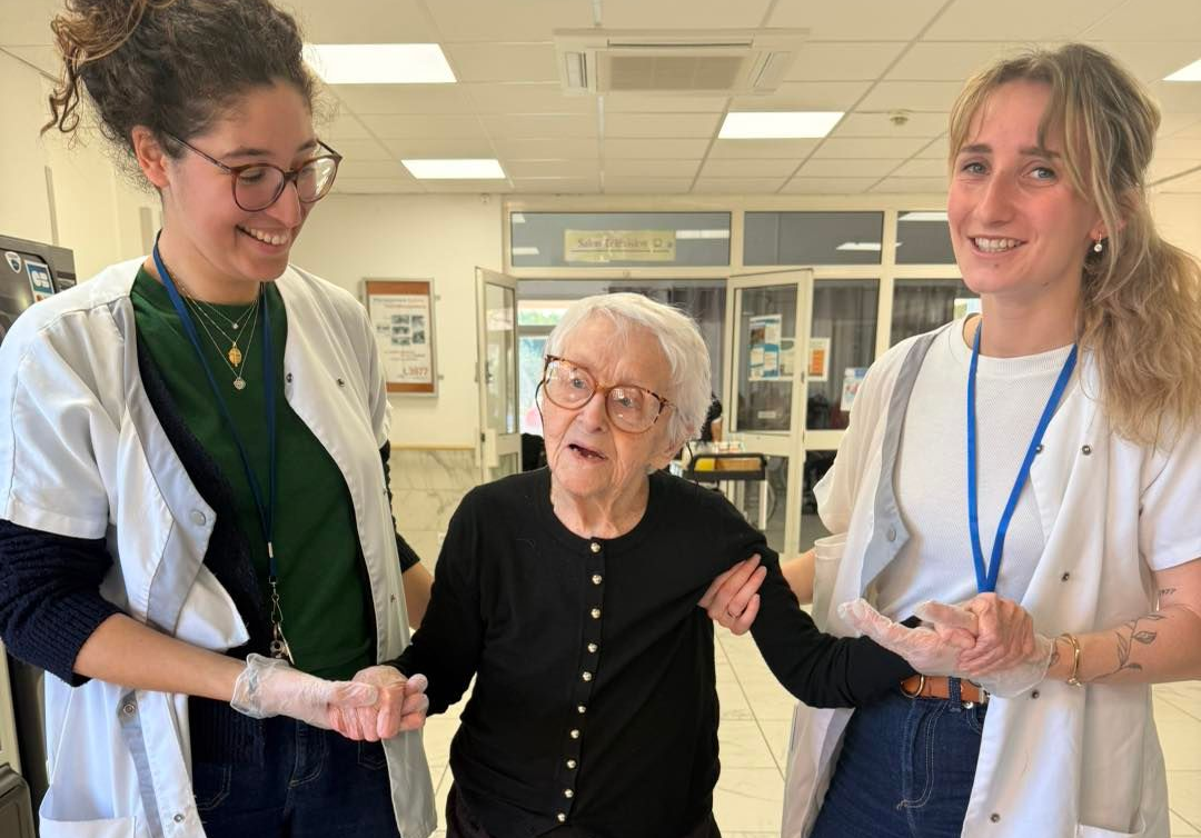 Une femme âgée se fait accompagner en balade par deux aides-soignantes.