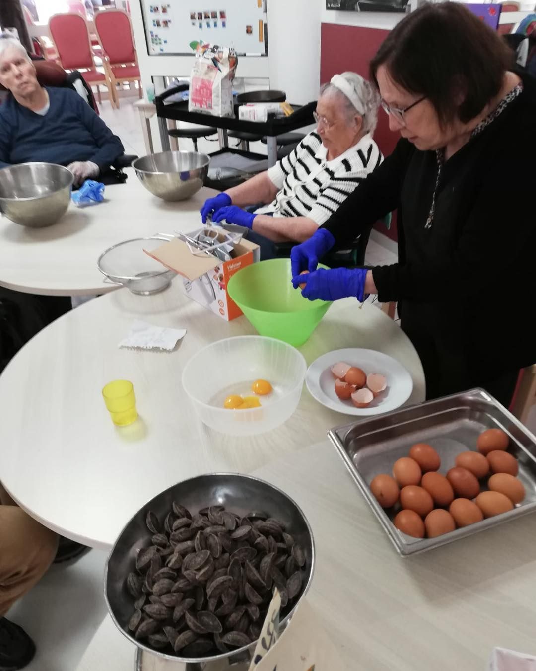 Des personnes dans une cuisine trient des œufs et des ingrédients dans des bols sur une table