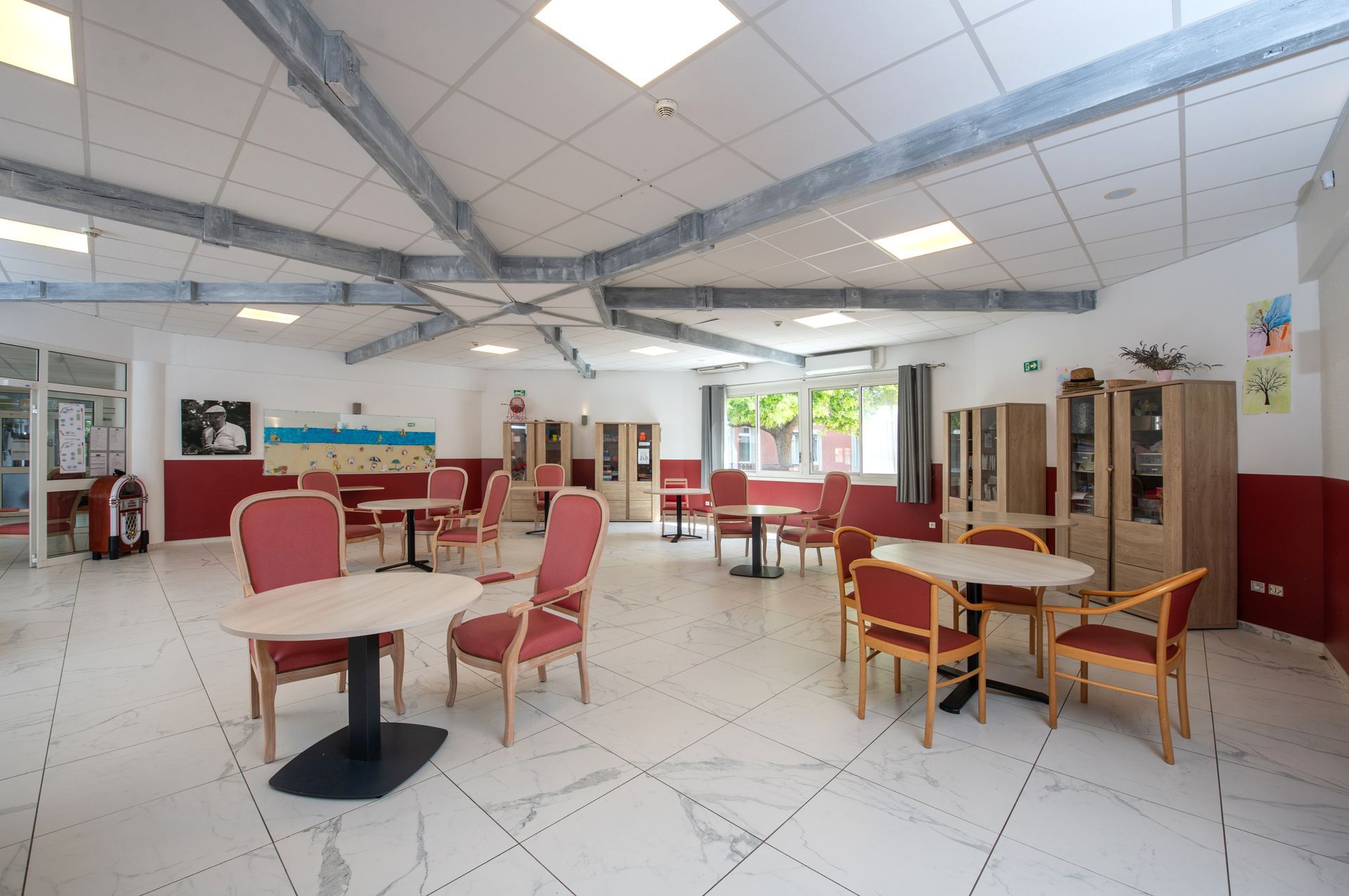 Une salle à manger commune spacieuse et bien éclairée, avec tables et chaises.