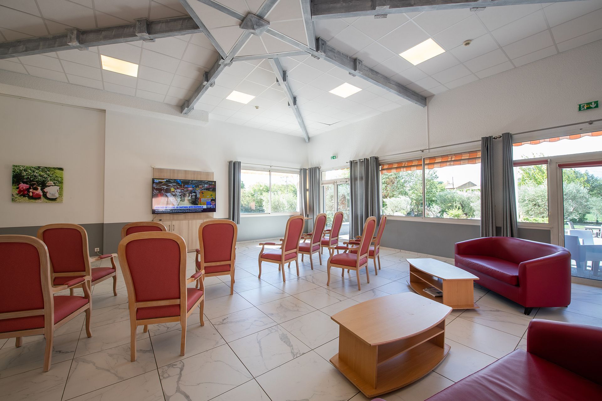 Un salon lumineux avec des fauteuils et des canapés rouge.