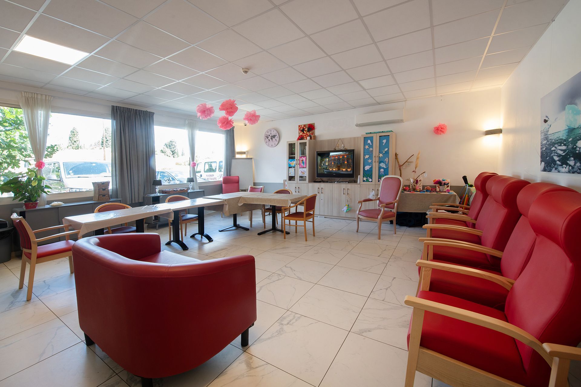 Une salle commune avec des fauteuils rouges.