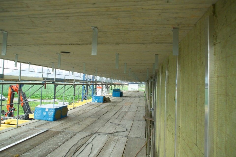 Baustelle: Innenansicht eines unfertigen Gebäudes mit Dämmung, Gerüst und Holzboden.