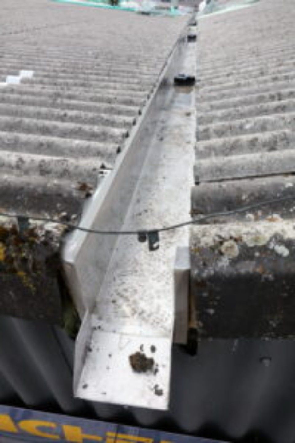 Nahaufnahme einer verwitterten, metallenen Dachrinne auf einem Wellblechdach.