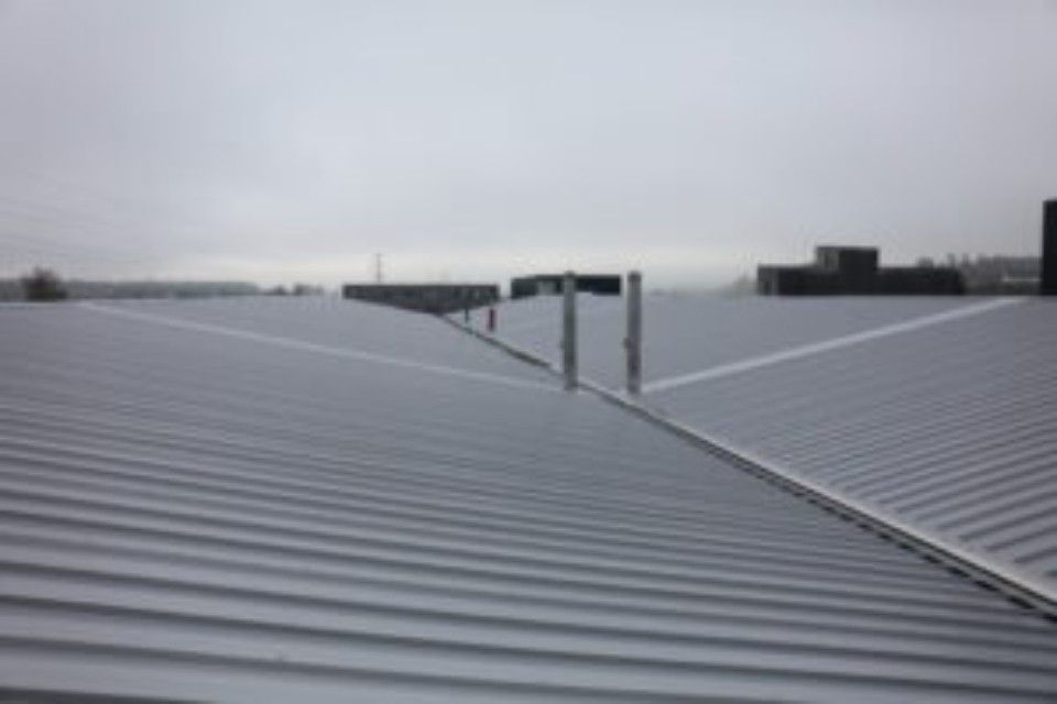 Metalldach mit Dachfirsten, bedeckter Himmel.