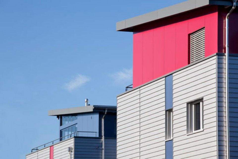 Modernes Gebäude mit roten und blauen Akzenten vor blauem Himmel.