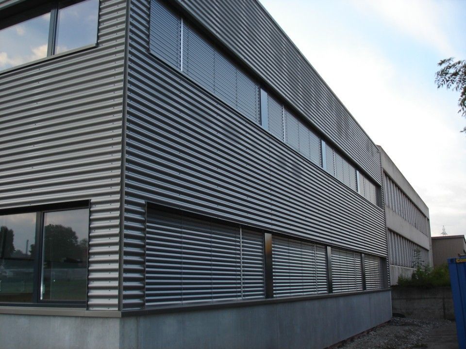 Gebäudeaussenfassade aus Wellblech mit Fenstern und Jalousien.