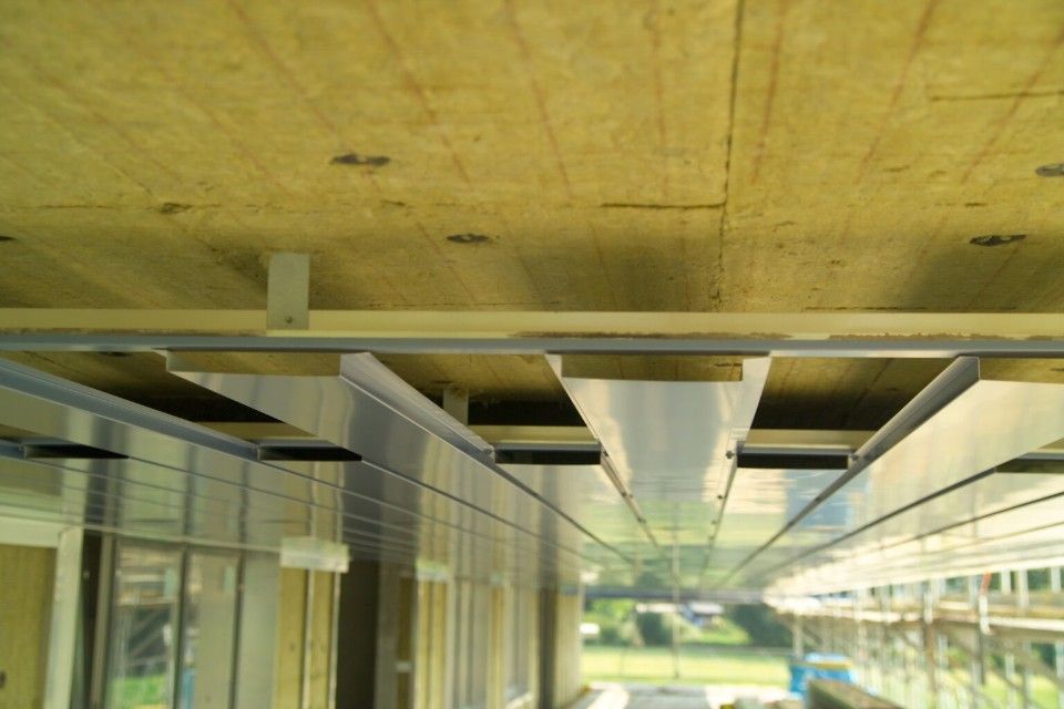 Blick auf eine Decke mit Isolierung, Metallrahmen und einen Blick auf die Aussenfassade des Gebäudes.