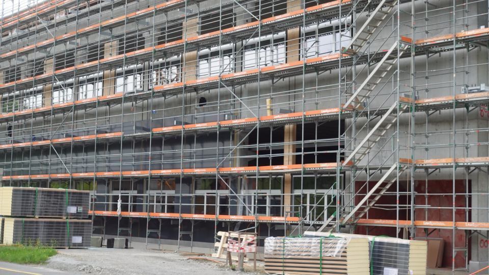 Ein Baugerüst umgibt ein im Bau befindliches Gebäude, vermutlich für Aussenarbeiten.