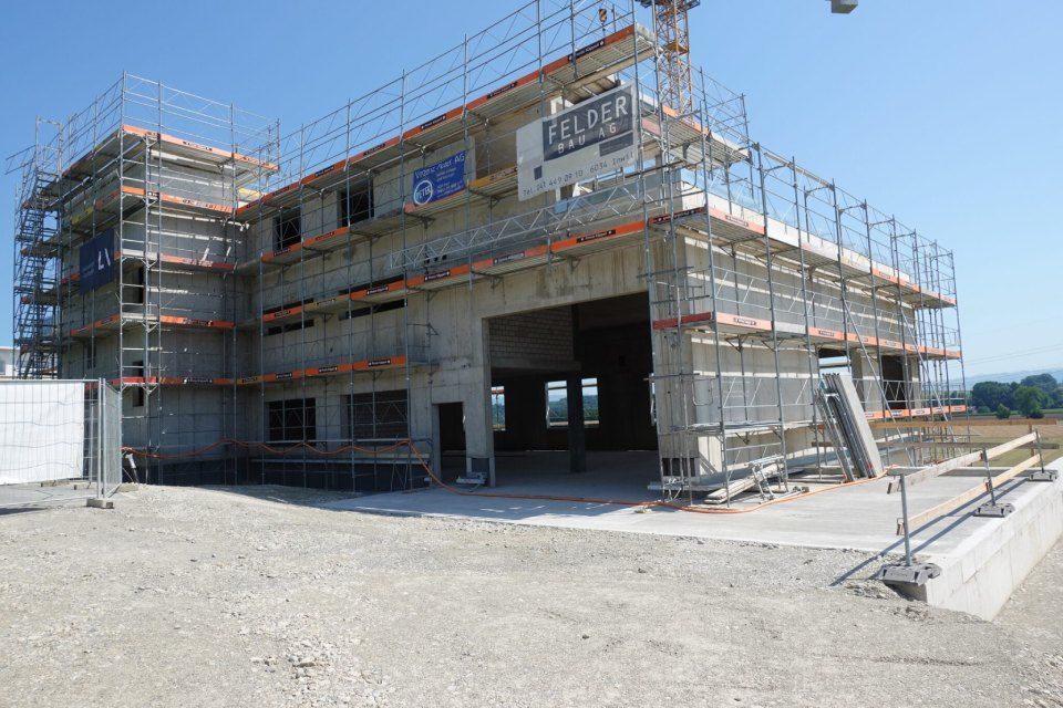 Eine im Bau befindliche Immobilie mit Gerüst und Sicherheitsnetzen an einem sonnigen Tag.