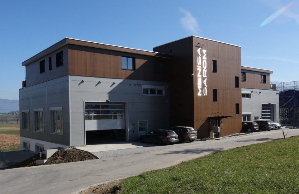 Modernes Gebäude mit braun-grauer Fassade, Garagentoren, geparkten Autos und dem Schriftzug „Hotel Kütz“.