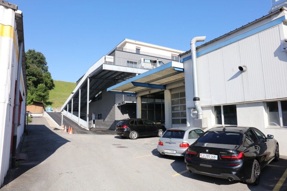 Autos parkten vor einem Gebäude mit Rampe, darüber ein blauer Himmel.