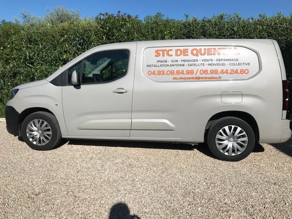 Fourgonnette grise STC de Quental avec logo et coordonnées, garée à l'extérieur.