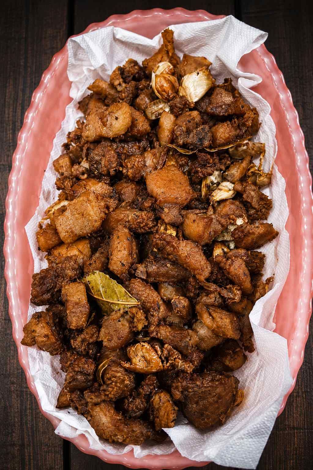 Bandeja de trozos crujientes de aperitivo frito sobre papel blanco en un plato con borde rosa.
