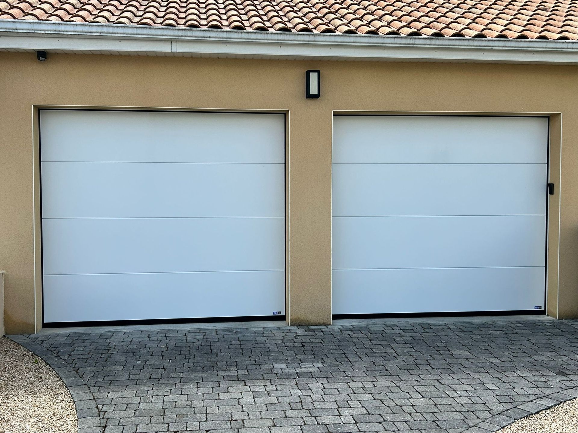 Portail et clôture en bois et métal noir devant une maison moderne avec boîte aux lettres et petit aménagement paysager.