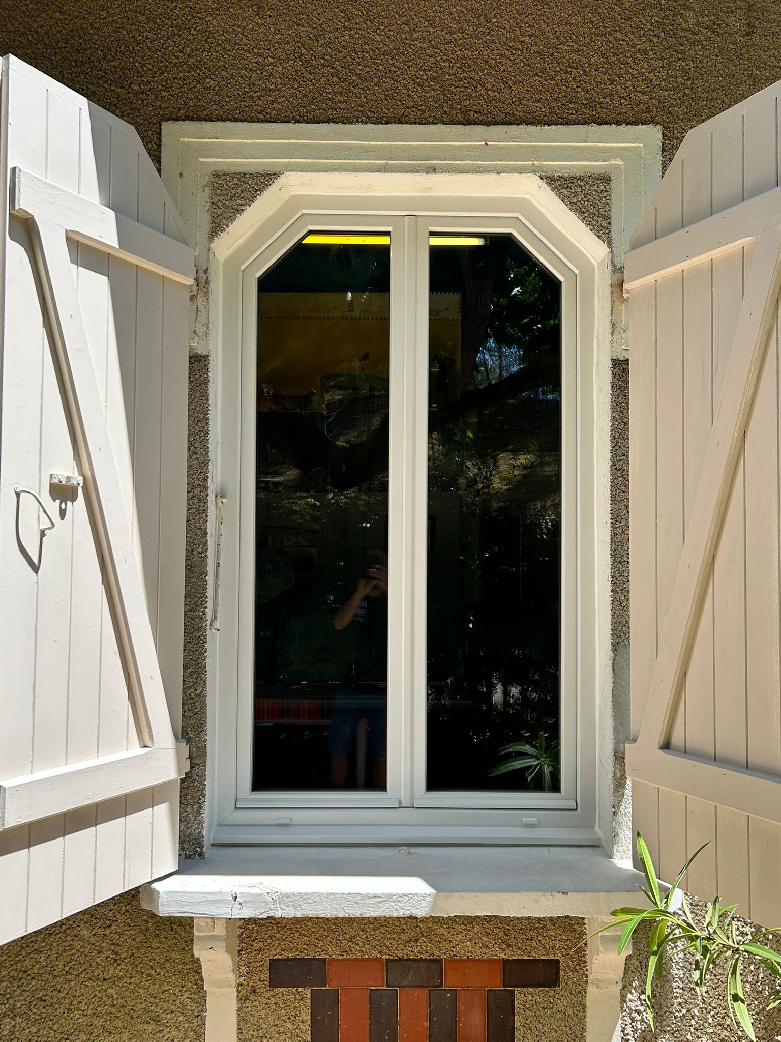 Porte d'entrée marron à rayures horizontales et panneau en verre dépoli, encastrée dans une entrée en retrait.