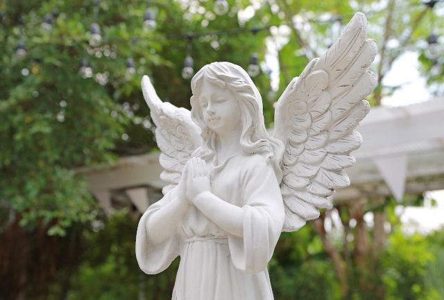 Una estatua de un ángel con las manos juntas en oración.