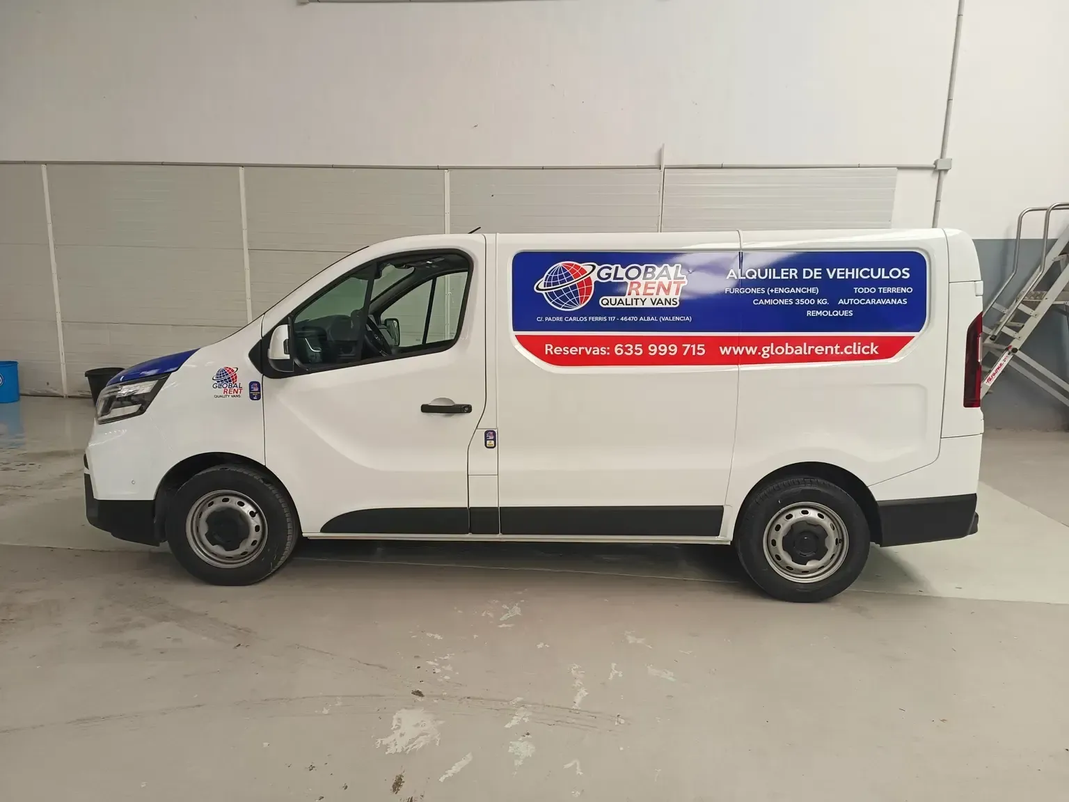 Furgoneta de servicio de color blanco con el logotipo de la empresa en azul y rojo estacionada en el interior.