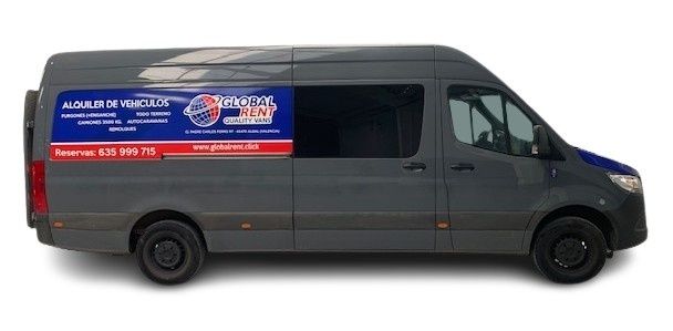 Furgoneta gris con logotipo estacionada en un almacén. Se ve otro vehículo al fondo.