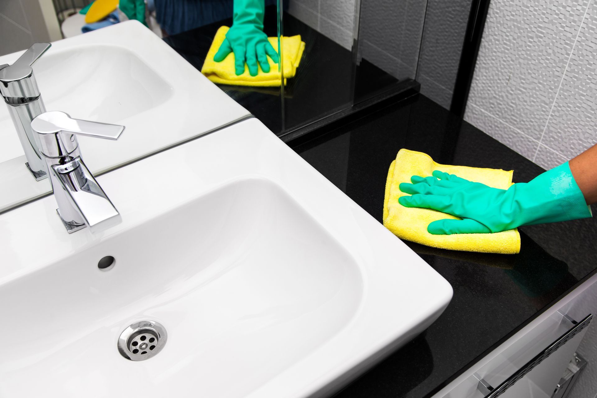 Unterhaltsreinigung eines Waschbeckens mit Tuch und Handschuhen