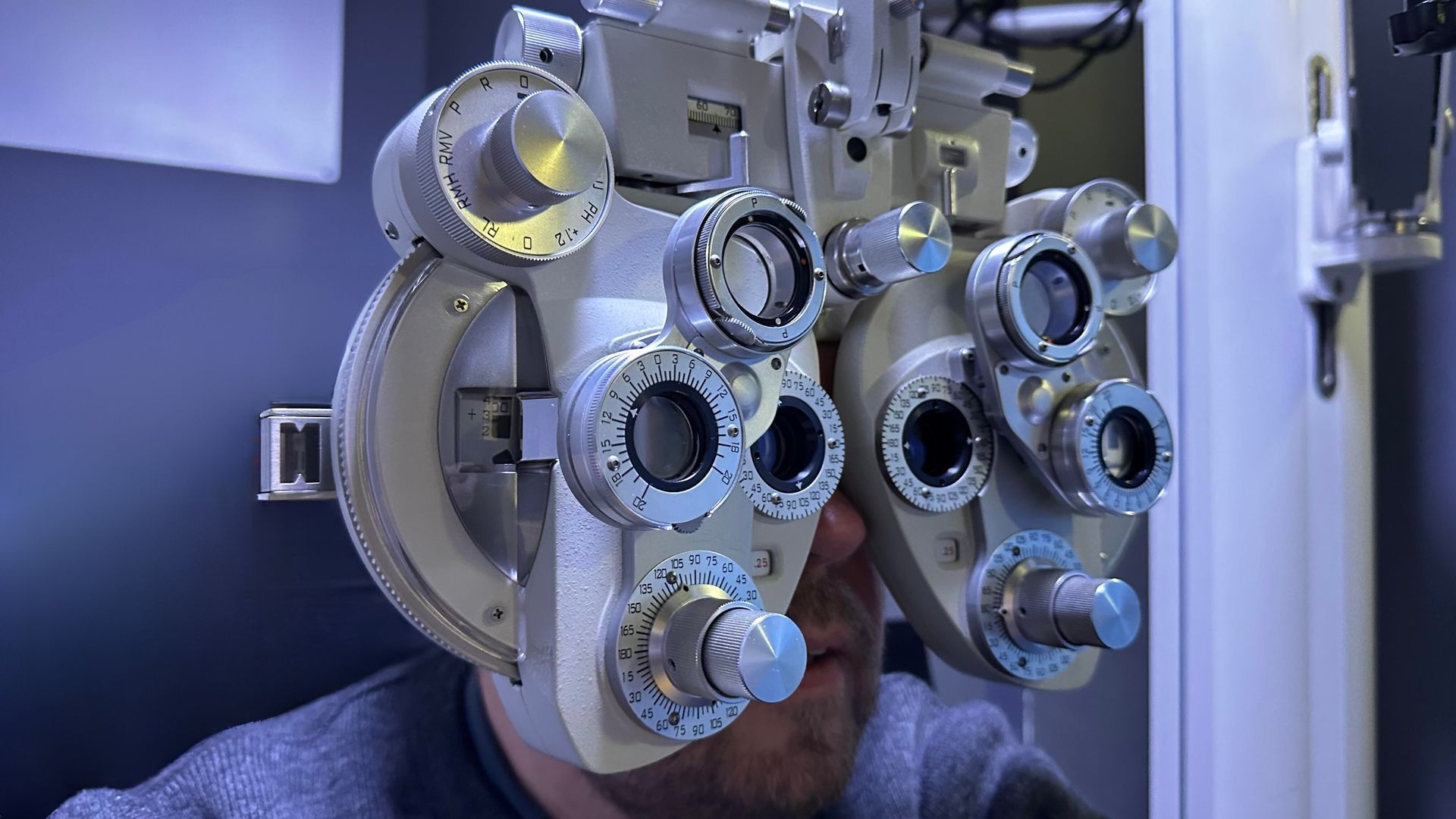 Un homme subit un examen ophtalmologique à l'aide d'un phoroptère dans un cabinet d'ophtalmologie.