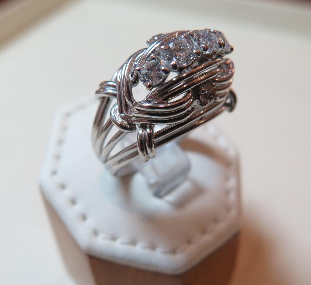 Gros plan sur une bague en argent et diamants présentée sur un présentoir blanc.