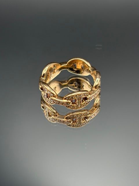 Gros plan de mains tenant une bague avec une pince à épiler sur un établi, avec des lumières floues en arrière-plan.