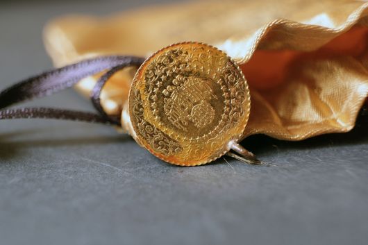 Gros plan d'une pièce d'or posée sur un ruban d'or souple sur une surface grise