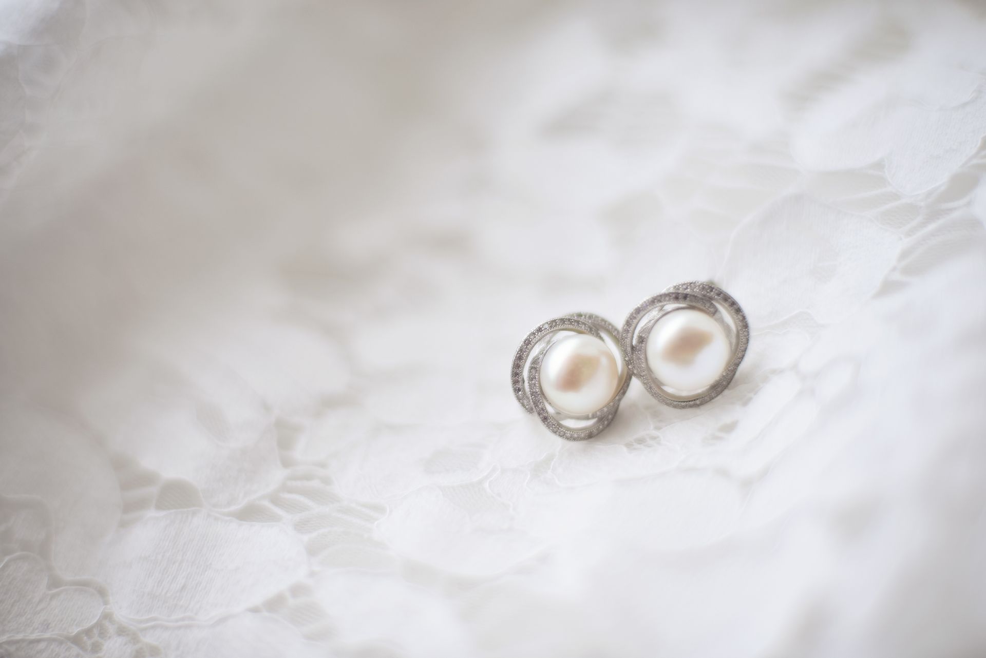 Boucles d'oreilles pendantes en or et cristal transparent sur fond beige
