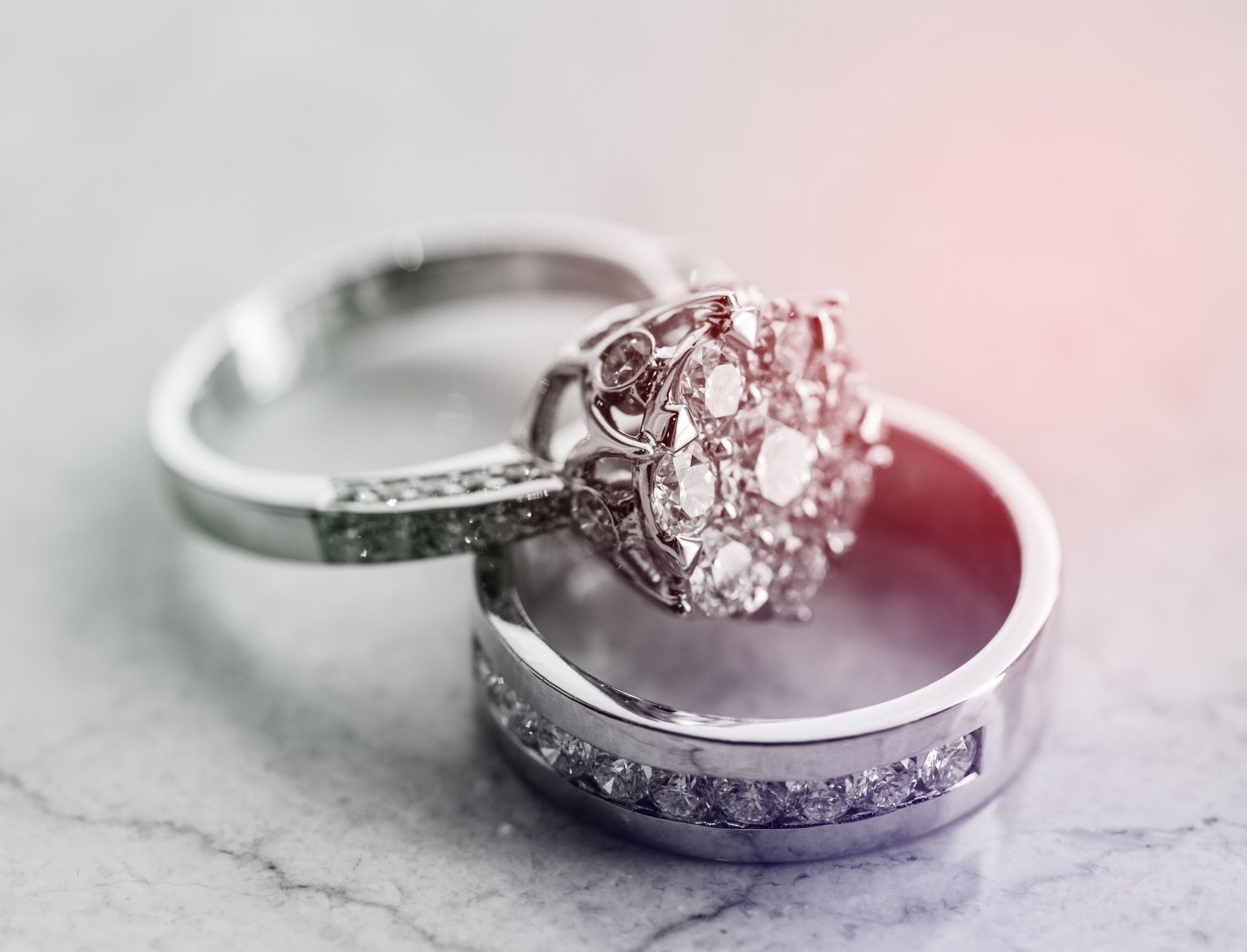 Gros plan de mains tenant une bague avec une pince à épiler sur un établi, avec des lumières floues en arrière-plan.