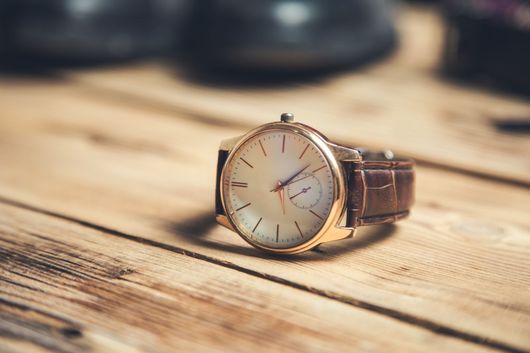 Montre-bracelet en or rose posée sur une table en bois avec un arrière-plan légèrement flou.