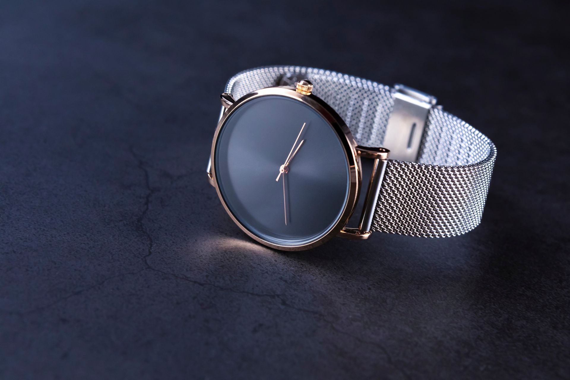 Montre-bracelet en maille argentée avec cadran rond foncé sur fond foncé