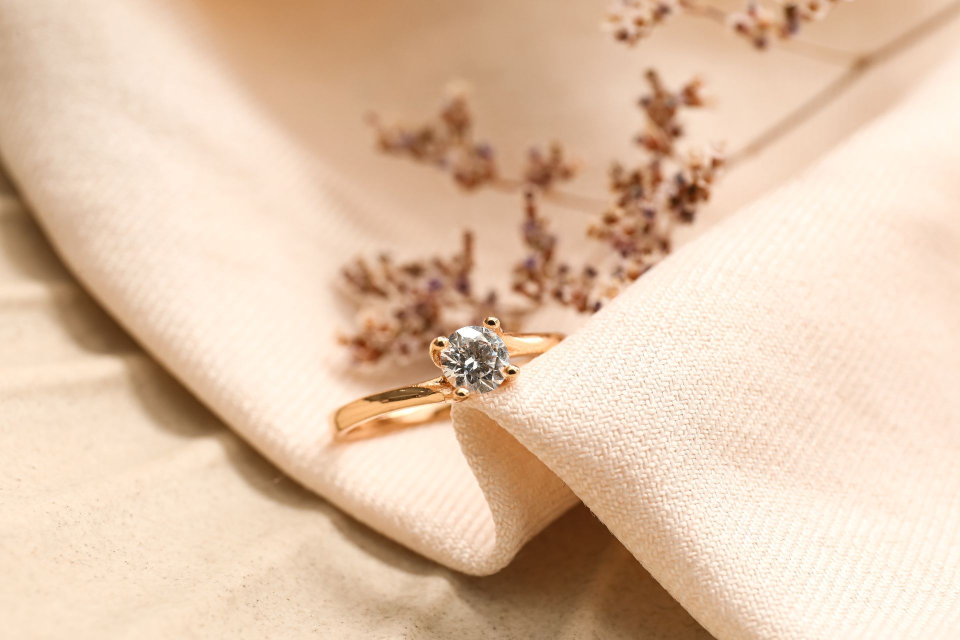 Bague en or ornée d'un gros diamant posée sur une surface en bois sous une lumière chaude